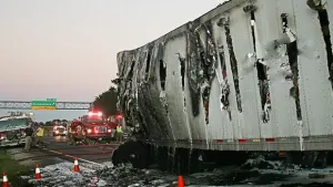 Firemen look at the remains of burned tractor (not visible) and trailer.